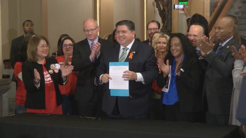 Gov. JB Pritzker celebrated with legislative leaders and advocates after he signed an assault...